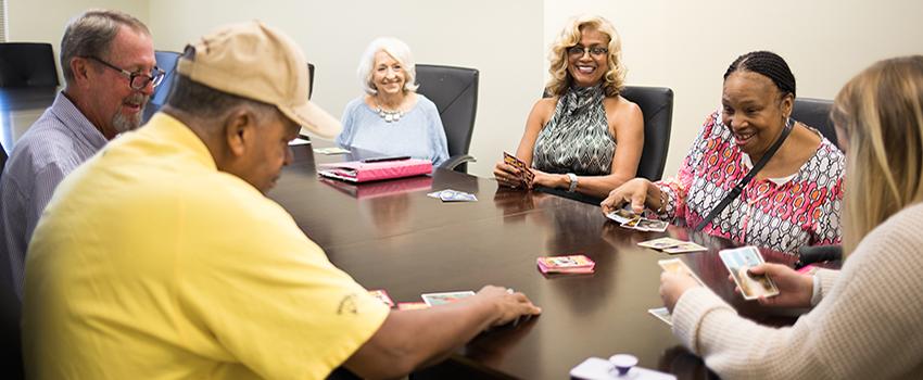 Elderly people sitting around table smiling.