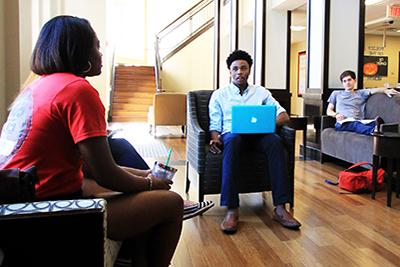 People working on laptops in a common area in housing.